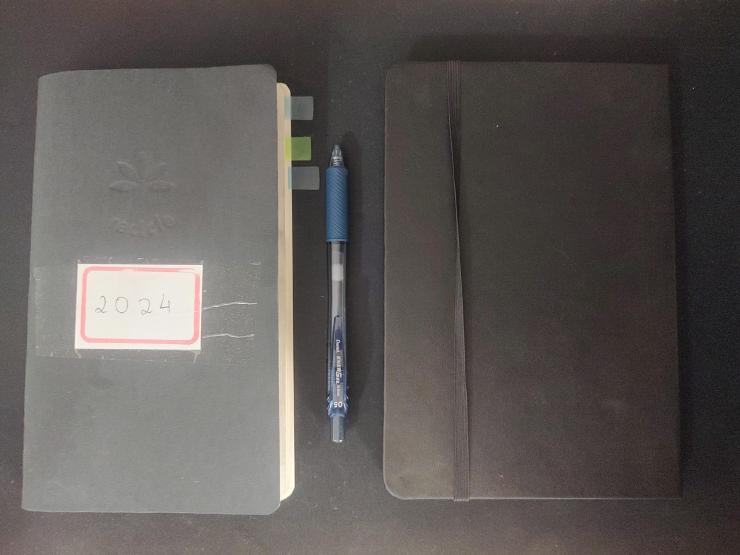 Two notebooks with a pen between them